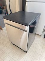 Front view of stainless steel portable dishwasher with black top and casters