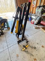 Overall view of folded 2-ton shop crane and separate load leveler with chains on floor