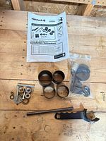 Full kit layout including cups, threaded rod, hardware, spanner wrench, sealed bag and manual