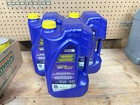 Three purple jugs of Royal Purple 5W-30 full synthetic motor oil with yellow caps, side view