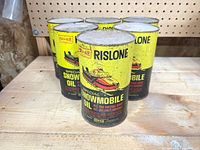 Five Rislone Special Snowmobile Oil cans on wood surface