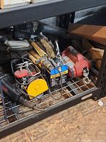 Three hoists stored on shelf, showing boxed unit, red hoist, cables and remotes
