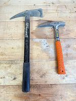 Council Tool black rock pick and Estwing silver rock pick side by side on wooden surface