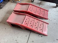 Oblique view of both red metal ramps showing side profile and perforated platforms