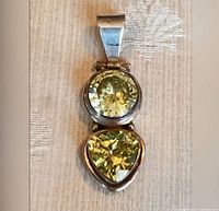 Front view of sterling silver pendant showing round and trilliant yellow-green stones