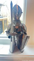 Front view of silver metal knight bottle holder showing sword and shield