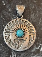 Front view showing turquoise cabochon, relief design, and bail