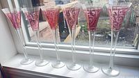 Six ruby etched champagne flutes lined on windowsill
