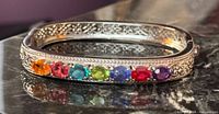 Front view of bangle showing seven colored stones and filigree detail
