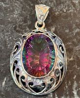 Front view of sterling silver pendant showcasing oval mystic topaz and filigree frame