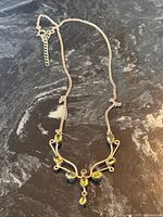 Full view of sterling silver peridot lariat necklace on dark surface