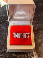 Ring in presentation box, front view showing alternating stones