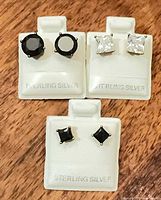 Three pairs sterling silver stud earrings on display cards