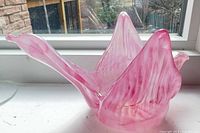 Side view of pink sculptural glass bowl on windowsill