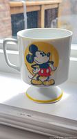 Front view of white pedestal mug with Mickey Mouse graphic