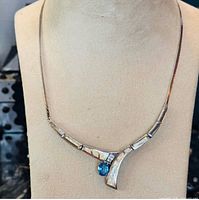 Front view of necklace on display bust showing opal inlay and blue topaz drop