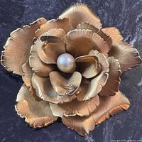 front view showing layered gold petals and faux pearl center