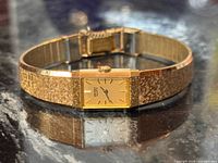 Front view of Seiko gold-tone wristwatch on black stone surface