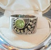 Front view of ring showing peridot stone and ornate bead swirl design