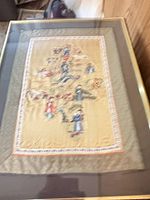 Full view of framed embroidered panel under glass