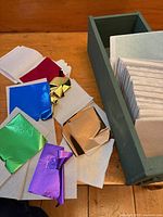 Foil sheets of various metallic colours on backing beside green drawer