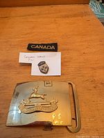 Belt buckle, pin badge and patch grouped on table