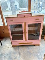 Front view of pink wooden hutch showing glass doors and overall structure