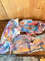 Overview of three hand-dyed merino wool roving batts on table