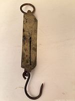 Full view of brass spring balance scale showing hook and ring