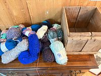 Wooden crate beside pile of assorted yarn skeins