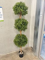 Full view of tall faux three-ball topiary tree in pot