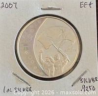Coin in cardboard flip showing reverse Olympic Flag Bearer design