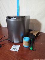 Front and side view of grey countertop composter with power cord, filter cartridge, boxed filter and roll of liners