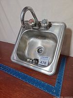 Top view of stainless bar sink with attached faucet and loose drain parts