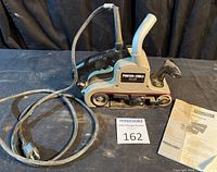 Full view of belt sander with power cord and manual
