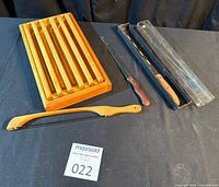 All items laid out: slotted bread board, Samurai bread knife with packaging, bread bow knife