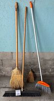 All four brooms standing against wall
