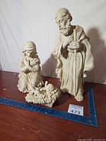 Joseph, Mary, and baby Jesus figures displayed with ruler for scale