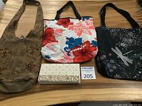 Overview of four bags: beaded clutch, hibiscus print tote, dragonfly print tote, brown embroidered sling tote