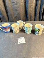 Group of five assorted coffee mugs displayed together