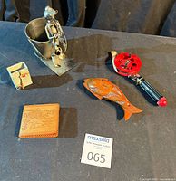 Group shot of all five items: ice rod, metal sculpture, pen holder, wooden fish, wallet
