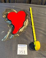 Front view with tape measure shows overall dimensions and color contrast between red heart and silver backplate