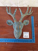 Front view of beaded deer head with ruler for scale
