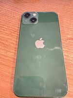 Rear view of dark green iPhone 13 showing dual cameras and Apple logo
