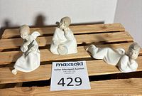 Front view of three Lladro porcelain winged child figurines