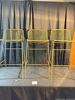 Front view of three matching brushed-gold metal stools
