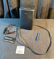 Front view of black Astro 6 L mini fridge with cords