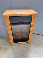 Full front view of Heat Surge fireplace heater showing oak cabinet, firebox with flame effect and added stabilizer strips