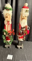 Full view of both wooden Claus figures standing side by side