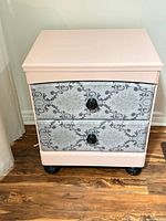 Front view of pink and gray two-drawer nightstand with patterned drawers and black knobs